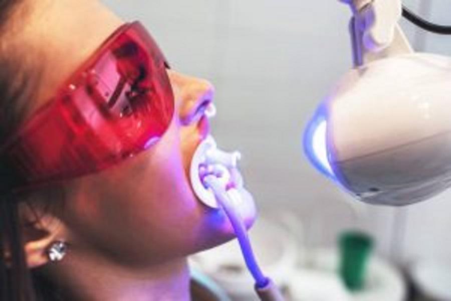 Woman getting teeth whitening in dental office