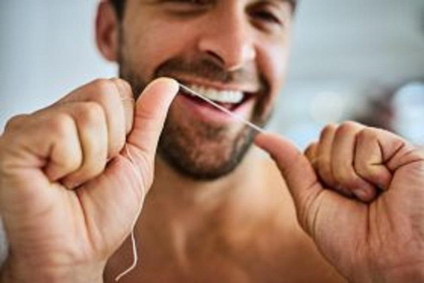 Smiling man flossing his teeth