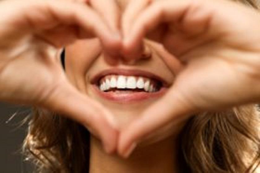 Woman forming heart shape with her hands around her smile