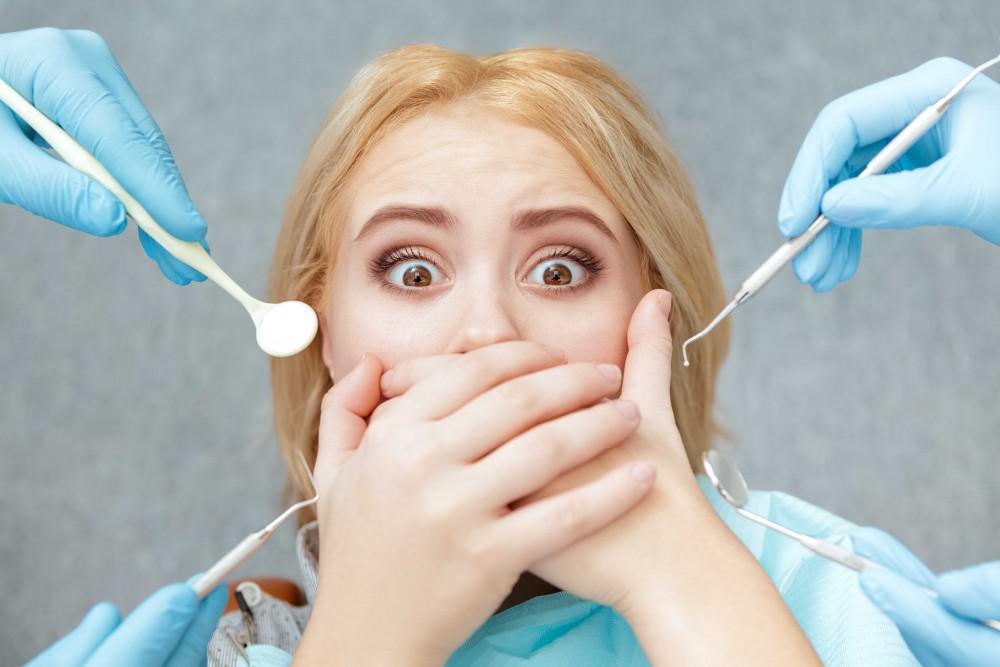 Woman covering her mouth while surrounded by dental tools