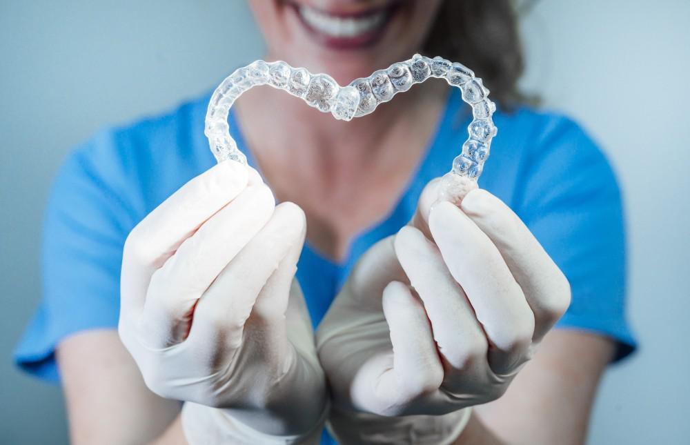 Woman holding up two Invisalign retainers