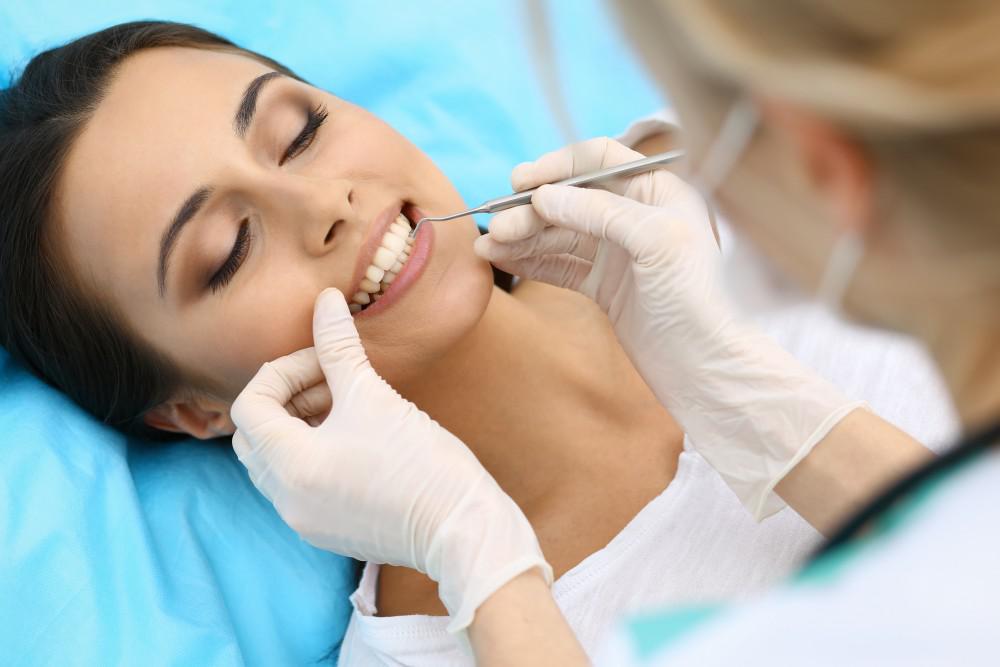 Woman showing teeth in dental office as dentist works on her teeth