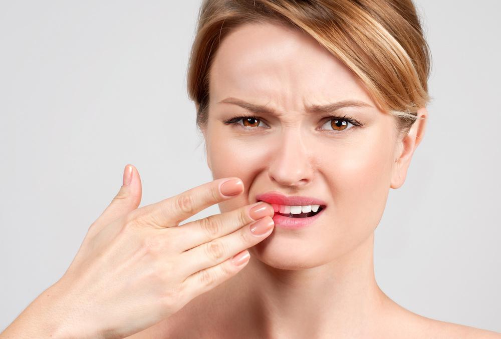 Woman holding her hand up to her teeth in pain