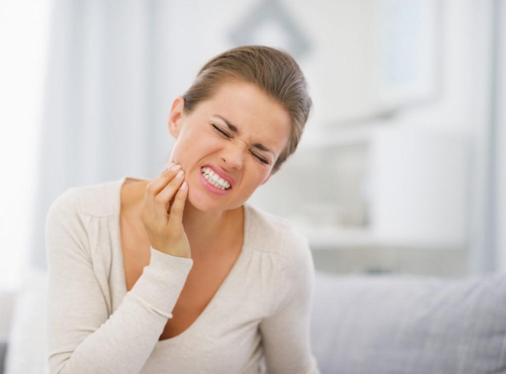 Wincing woman holding her jaw in pain
